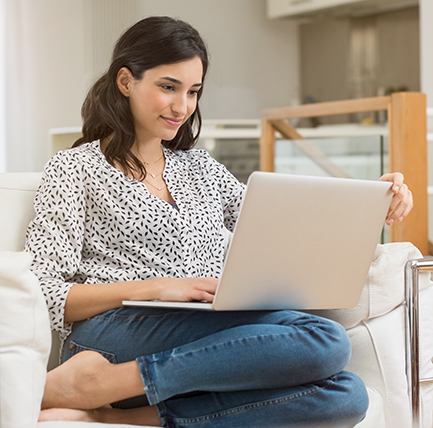 Woman at home using laptop searching for symptoms of bowel cancer.