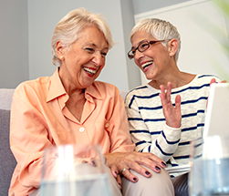 two women laughing on couch